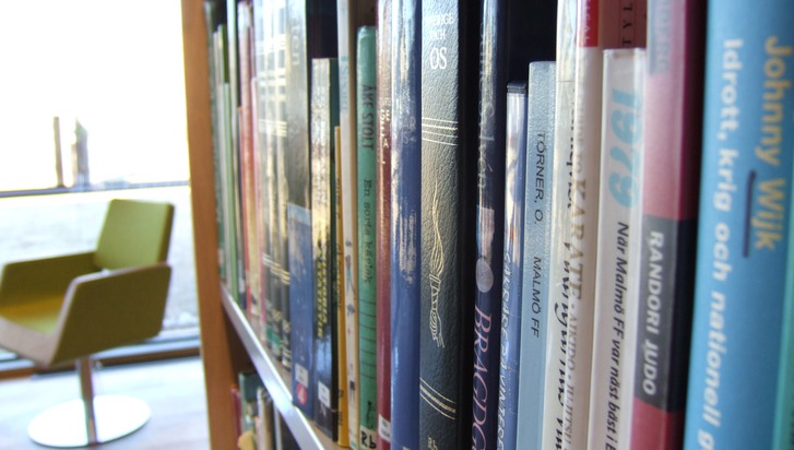bokhyllor på ett bibliotek, i bakgrunden en läsfåtölj