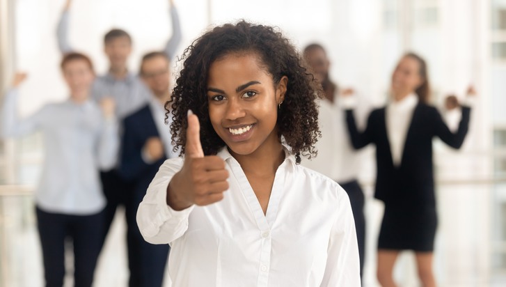 Headshot smiling african female looking at camera showing thumbs up overjoyed diverse employees in background. Leadership, successful career, client received best services and recommendation concept