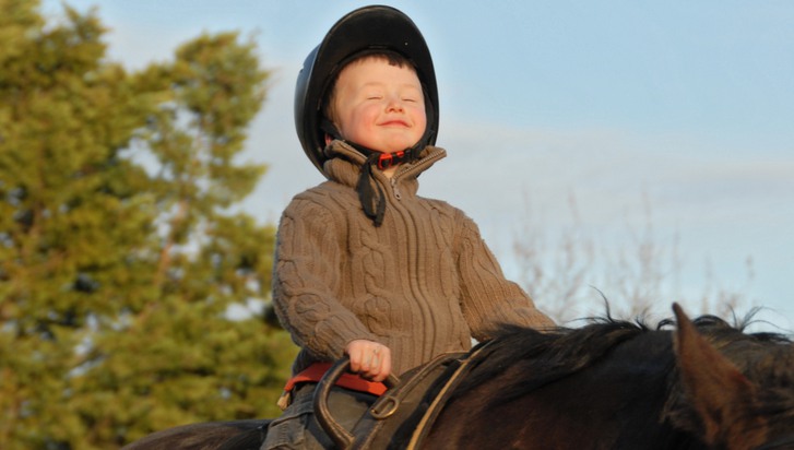 pojke på hästryggen som ler i kapp med solen