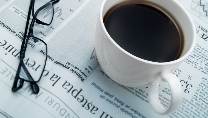 ett par glasögon och en kopp kaffe ovanpå en dagstidning